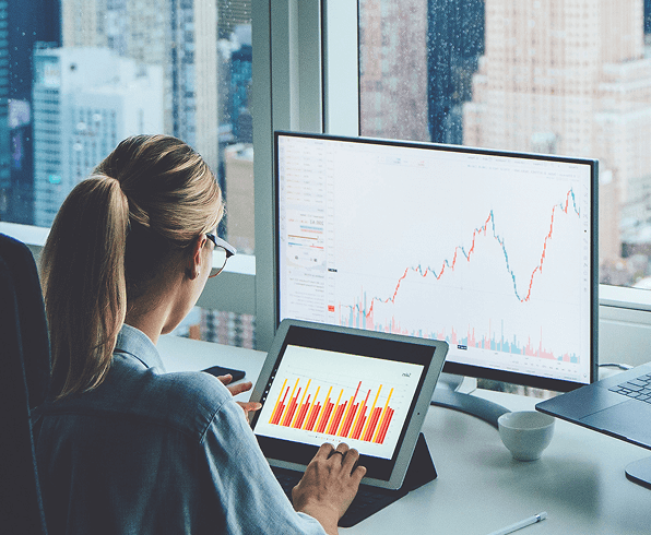 Woman staring at charts on her tablet and computer screen 