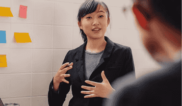 A professional woman explaining ideas during a presentation with sticky notes.