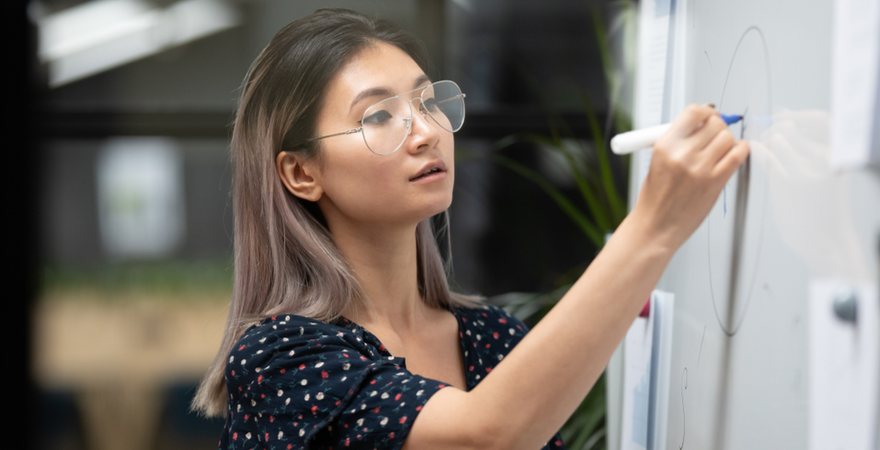 A female postgraduate student drawing a diagram on a whiteboard as part of the ADEPT learning approach.