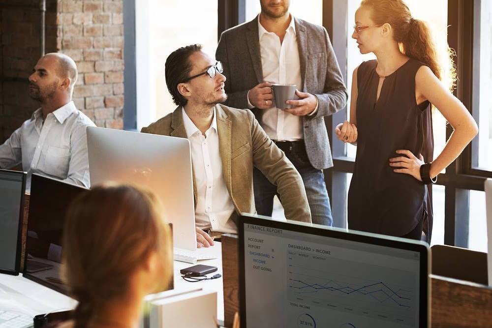 A data analyst works with a data visualisation program on a monitor in a busy office