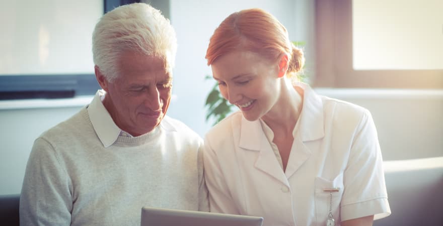 A female aged care nurse using an iPad to show a patient his digital health record.