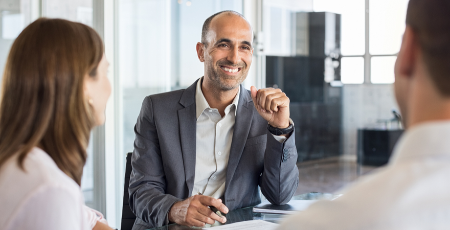 An analyst meets with two coworkers at a conference table.
