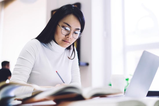Mid-career professional in Singapore studying for a Master of Analytics on a laptop.