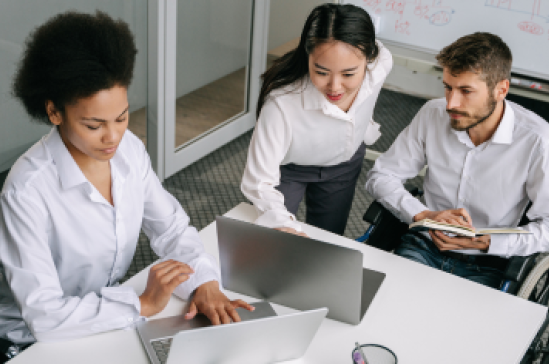 Three people in an office setting looking at laptop screens. 