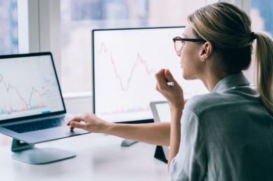 Woman analysing financial graphs and statistics on computer