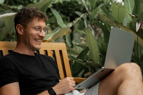 A person sitting outdoors on a wooden bench.