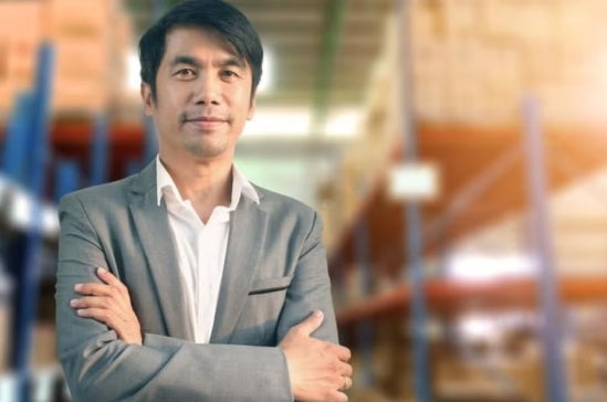 A social entrepreneur standing and smiling with his arms crossed