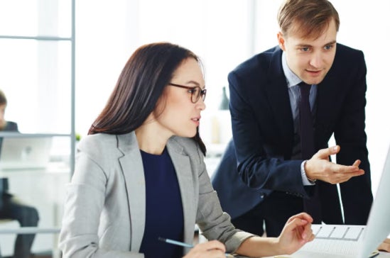 Man and woman reviewing work on a computer in a FinTech company office
