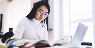 Mid-career professional in Singapore studying for a Master of Analytics on a laptop.
