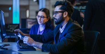 Cyber security professionals reviewing threat data on screens.
