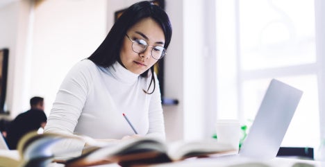 Mid-career professional in Singapore studying for a Master of Analytics on a laptop.