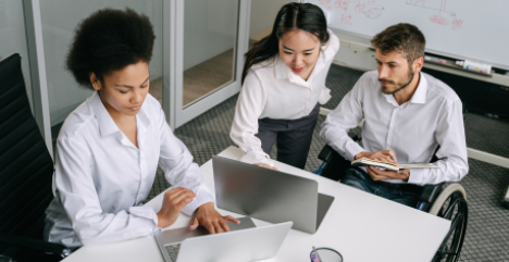 Three people in an office setting looking at laptop screens. 