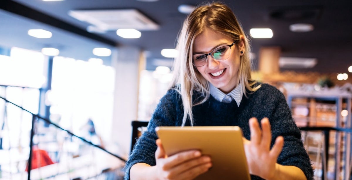 A woman with glasses scrolling on her tablet.