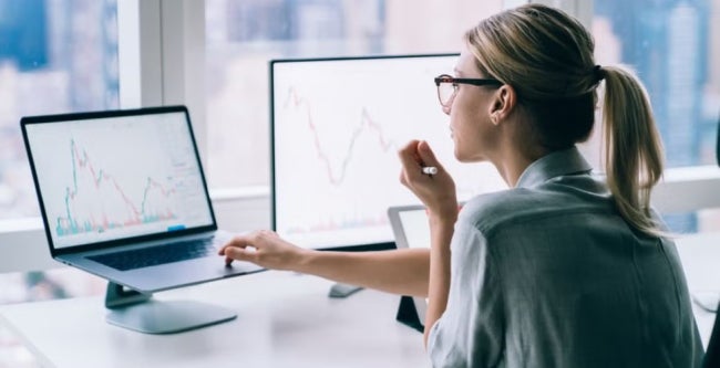 Woman analysing financial graphs and statistics on computer