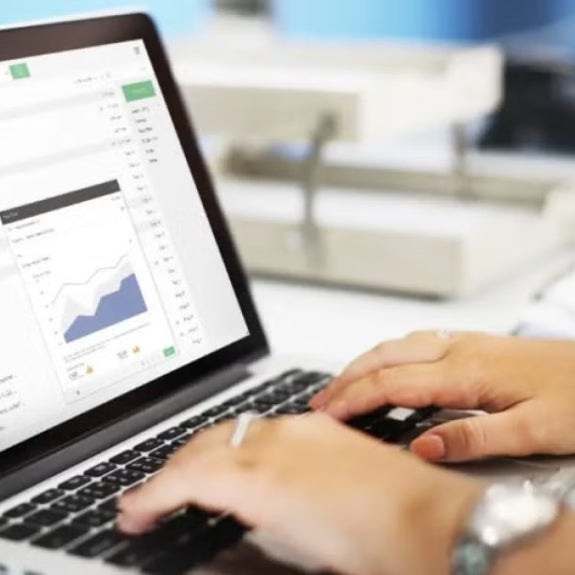 Hands typing on a laptop keyboard with an email inbox open on screen, displaying a data chart, representing digital analytics or data review.