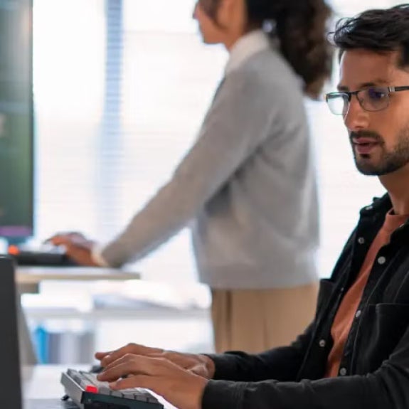 A cybersecurity analyst with eyeglasses working on a laptop.