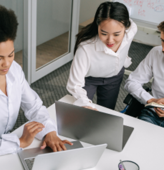 Three people in an office setting looking at laptop screens. 