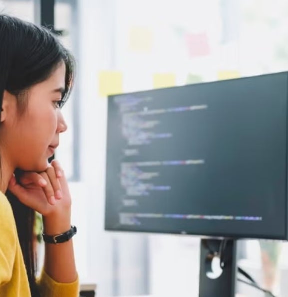 A data scientist studies code on a laptop and computer monitor.