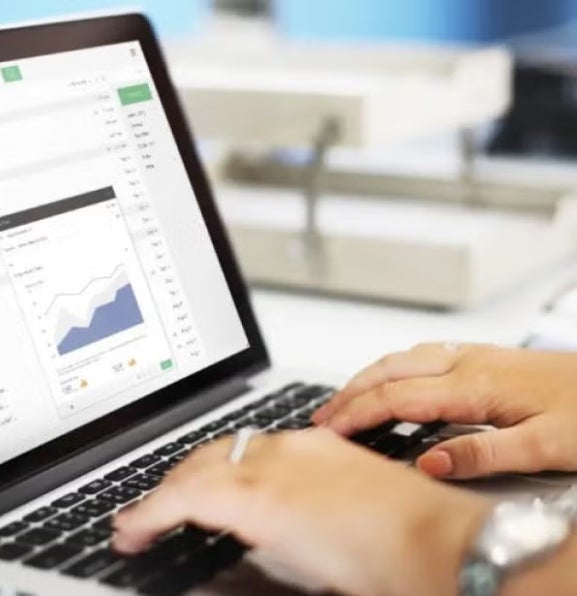 Hands typing on a laptop keyboard with an email inbox open on screen, displaying a data chart, representing digital analytics or data review.