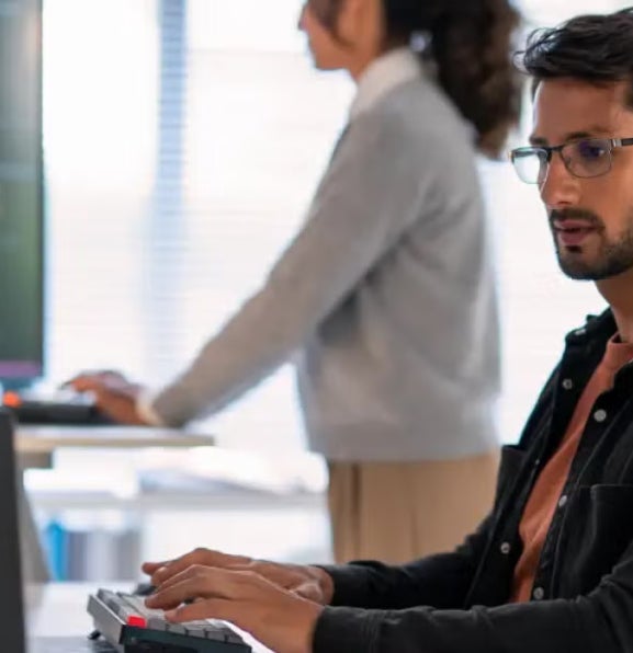 A cybersecurity analyst with eyeglasses working on a laptop.