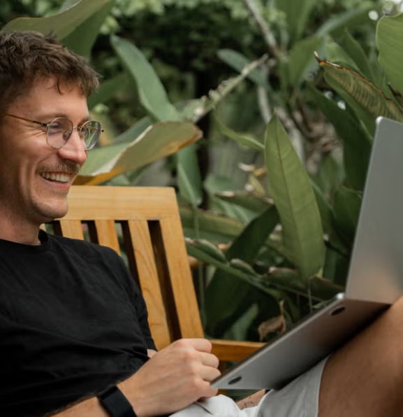 A person sitting outdoors on a wooden bench.