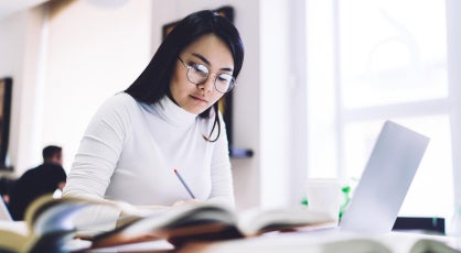 Mid-career professional in Singapore studying for a Master of Analytics on a laptop.