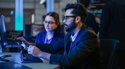 Cyber security professionals reviewing threat data on screens.