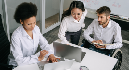Three people in an office setting looking at laptop screens. 