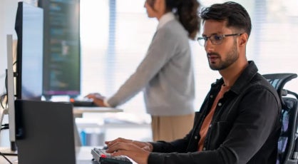 A cybersecurity analyst with eyeglasses working on a laptop.
