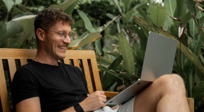 A person sitting outdoors on a wooden bench.