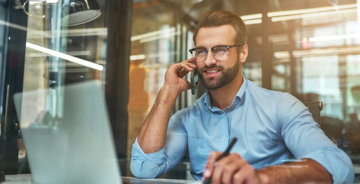 A stock market analyst reviews financial data on a laptop while sitting in a modern office.